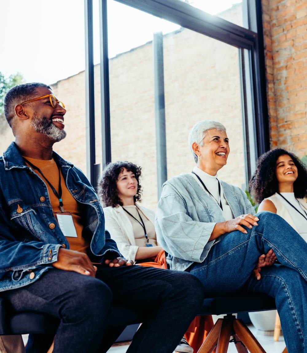 A facilitator leading a relaxed group conversation with program staff